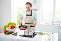 Photo of chef handsome mature man hold pan fry cook meat wear apron blue t-shirt home kitchen indoors Royalty Free Stock Photo