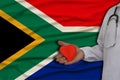 Photo of a child with a stethoscope in a professional uniform with a heart in his hands against the background of the national Royalty Free Stock Photo