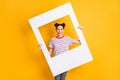 Photo of childish sweet young girl dressed striped t-shirt holding big photo frame isolated yellow color background