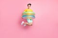 Photo of childish sweet young guy dressed yellow t-shirt jumping high inside swim circle pink color background