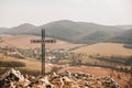 Photo of christian cross on the rock with perfect view and valley with hills  on background. Top of mountain with village and Royalty Free Stock Photo