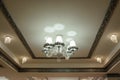 photo of a classic ceiling in white and golden colors and a chandelier hanged on it