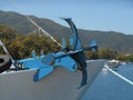 Photo of close up view to reddish and blue anchor standing on front part of fishing boat