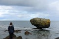 A photo closeup of a female tourist admiring the famous balance rock on the east coast of Graham Island, outside Skidegate