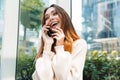 Photo closeup of happy charming woman smiling and talking on cellphone while sitting near window in building indoors Royalty Free Stock Photo