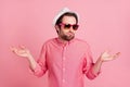 Photo of clueless ignorant young man shrug shoulders wear hat sunglass isolated on pastel pink color background Royalty Free Stock Photo