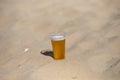 Photo of cold beer in the hot sand. Drops of water on glass. Thirsty concept. Summer time. Holiday. Copy space