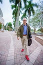 PHoto of a college professor walking on campus with blurry people in background