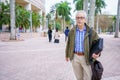 PHoto of a college professor walking on campus with blurry people in background