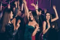 Photo of company celebrating prom at party in the night club dancing together laughing relaxing hands up wearing festive