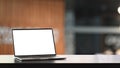 Photo of Computer laptop with white blank screen putting on modern wooden table with blurred living room as background. Royalty Free Stock Photo