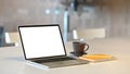 Photo of Computer laptop with white blank screen putting on white working desk with coffee cup and notebook . Royalty Free Stock Photo