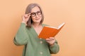 Photo of concentrated school teacher old lady hold literature touch specs enjoy nonfiction materials isolated on beige