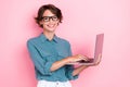 Photo of confidant lovely pretty girl with bob hairdo wear blue shirt eyeglasses comunicating on laptop isolated on pink