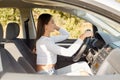 Photo of confident brown haired woman sitting on driver`s seat, opens door, looking away with serious look, enjoying her trip by