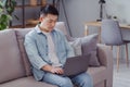 Photo of confident freelance programmer worker japanese man sit couch typing netbook wear casual shirt in home indoors