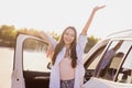 Photo of confident funny young woman wear white shirt rising arms open car door smiling outside city street
