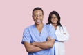 Portrait of confident mixed race male and female surgeons over pink background