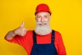 Photo of confident positive age man workwear overall red hard hat showing thumb up isolated yellow color background Royalty Free Stock Photo