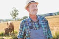 Confident Senior farmer standing against brown cow in field Royalty Free Stock Photo