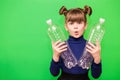 Photo of confused funny little girl holding plastic bottles and looking at camera isolated over green background