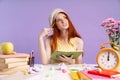 Photo of confused student girl writing in exercise book while doing homework