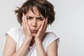 Photo of confused woman with short brown hair in basic t-shirt keeping hands over her face and frowning at camera Royalty Free Stock Photo