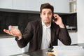 Confused young businessman talking by mobile phone. Royalty Free Stock Photo