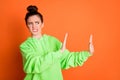 Photo of confused young woman wear green hoodie showing refusal gesture isolated vivid orange color background