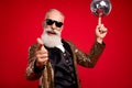 Photo of cool beard old man point you hold disco ball wear gold jacket eyewear isolated on red color background Royalty Free Stock Photo