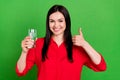 Photo of cool brunette millennial lady drink water show thumb up wear red shirt isolated on green color background Royalty Free Stock Photo