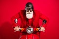 Photo of cool careful driver santa claus ride bike serious face wear goggles leather helmet suit on red color background