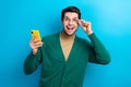 Photo of cool excited man wear green cardigan arm spectacles reading sms modern device isolated blue color background Royalty Free Stock Photo