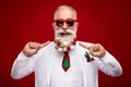 Photo of cool old grey hair santa man point balls on beard wear eyewear white jacket isolated on red color background Royalty Free Stock Photo