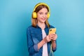 Photo of cool teen blond girl listen music from phone wear casual cloth isolated on blue color background Royalty Free Stock Photo