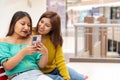 Photo with copy space of friends using a mobile in a shopping mall Royalty Free Stock Photo