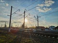 Photo of countryside with railway tracks, electric pillars against the background of the spring sky with clouds and the setting