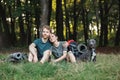 Photo of couple and a dog sitting in forest at summer with backpacks Royalty Free Stock Photo