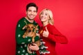 Photo of couple hold little cute dachshund lady raise thumb up wear ugly sweater isolated red color background Royalty Free Stock Photo