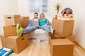 Photo of couple sitting on couch with laptop among cardboard boxes