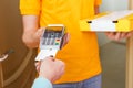 Photo of courier in yellow T-shirt with box with pizza and point of sale