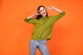 Photo of crazy brunette hairdo young lady show v-sign wear specatcles green shirt isolated on orange color background