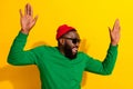 Photo of crazy carefree cheerful man dance raise palms wear sunglass red beanie green shirt isolated yellow color