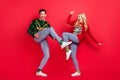 Photo of crazy careless couple dance celebrate scream wear ugly sweater jeans shoes isolated red color background