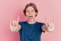 Photo of crazy excited guy happy positive smile show horns rock metal sign tongue-out brutal isolated pink color Royalty Free Stock Photo