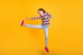 Photo of crazy fighter girl jump kick leg air wear striped shirt jeans shoes isolated yellow color background Royalty Free Stock Photo