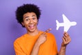 Photo of crazy funky young tourist guy directing forefinger demonstrate boeing airplane paper model isolated on purple Royalty Free Stock Photo