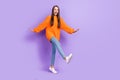 Photo of crazy funny inspired lady walk have fun wear orange pullover jeans sneakers isolated purple color background