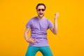 Photo of crazy musician guy play imaginary guitar wear sunglass purple t-shirt isolated yellow color background