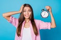 Photo of crazy nervous lady hand head hold alarm clock wear pink striped shirt isolated blue background